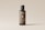 A sleek, cylindrical bottle with a minimalist design stands against a light neutral background. The label on the bottle reads 'Bottle Duo' in white text, and there is a QR code printed below it. The bottle's color is a muted brown with a black cap, and additional text is displayed vertically along the side.