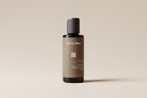 A sleek, cylindrical bottle with a minimalist design stands against a light neutral background. The label on the bottle reads 'Bottle Duo' in white text, and there is a QR code printed below it. The bottle's color is a muted brown with a black cap, and additional text is displayed vertically along the side.