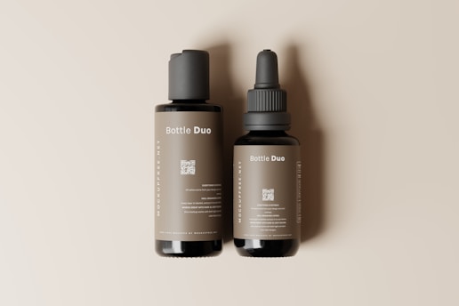 Two bottles are placed side by side on a neutral beige background. The larger bottle has a pump dispenser, while the smaller bottle features a dropper. Labels on both bottles read 'Bottle Duo' with detailed text below, including a QR code. The bottles have a sleek and minimalist design.