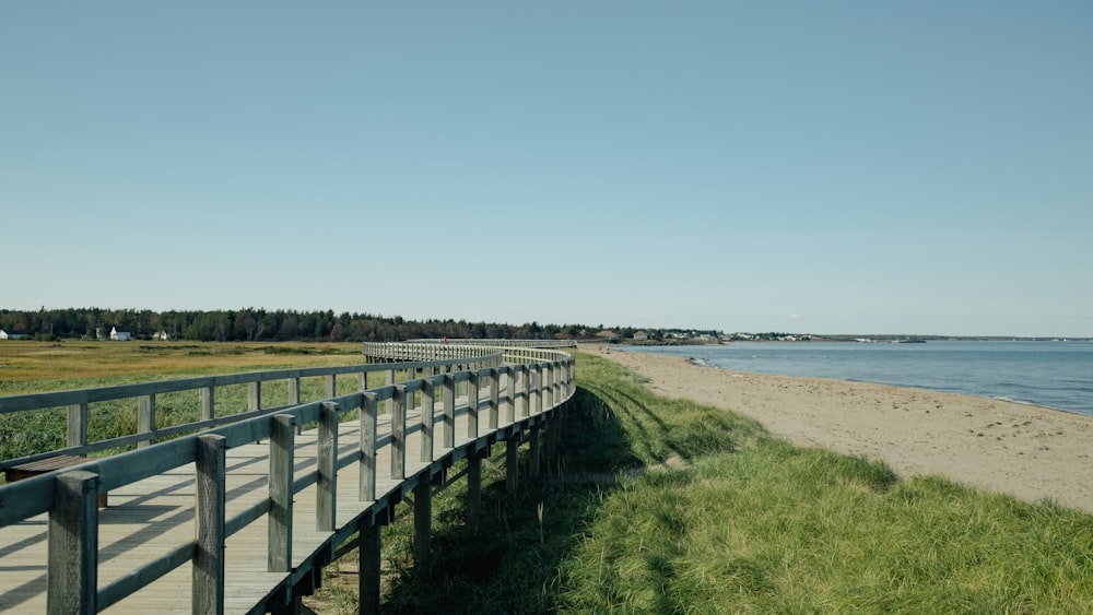 a wooden walkway next to a beach near a body of water