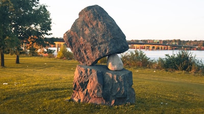 Outdoor shot of a large stone sculpture displayed in a sunlit garden.