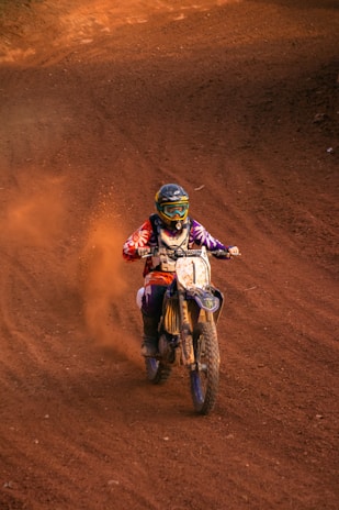 João Gabriel 'Bolachinha' racing fiercely on his motocross bike kicking up dirt.
