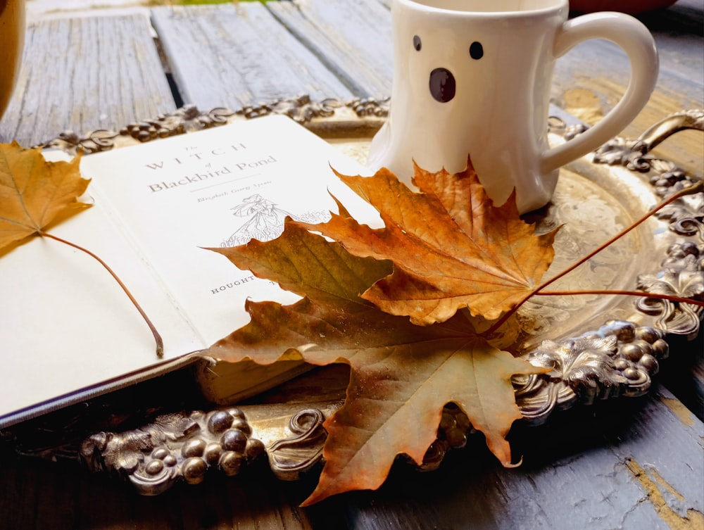 a cup of coffee and a leaf on a tray