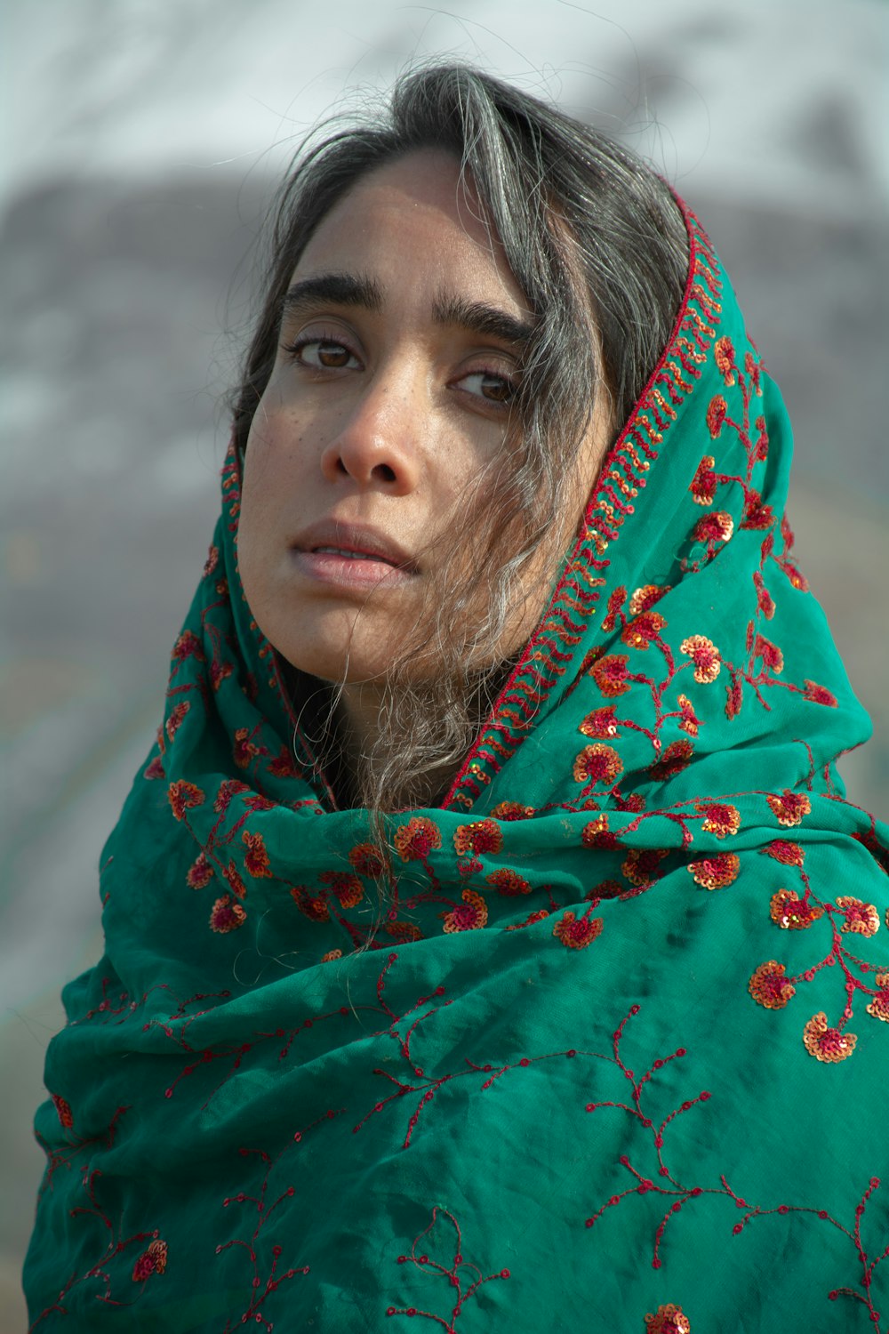 a woman wearing a green shawl with red flowers on it