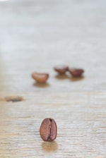 A close-up of aromatic coffee beans resting on a rustic wooden table, bathed in warm morning light.