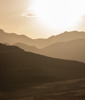 the sun is setting over the mountains in the desert