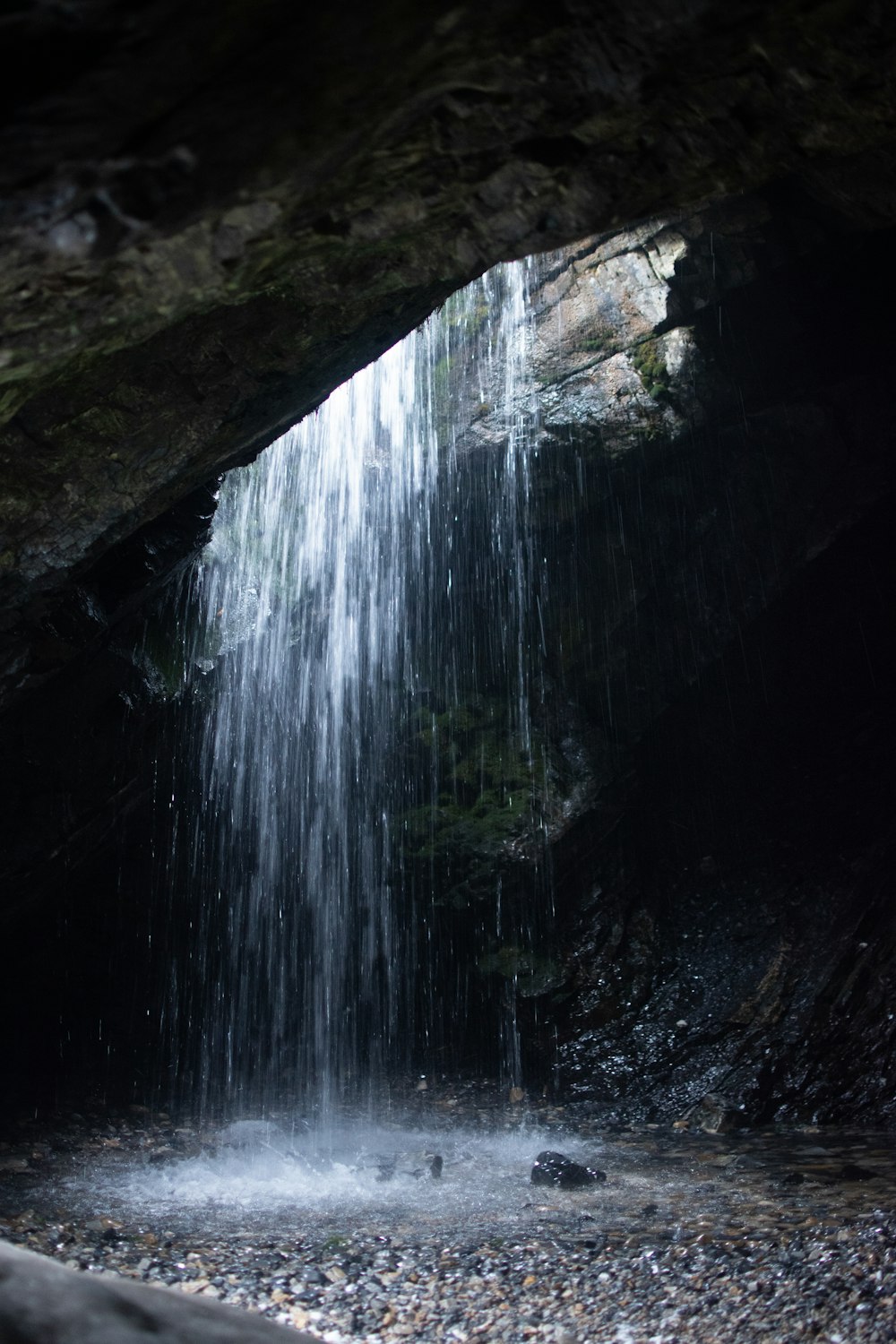 a small waterfall is coming out of a cave