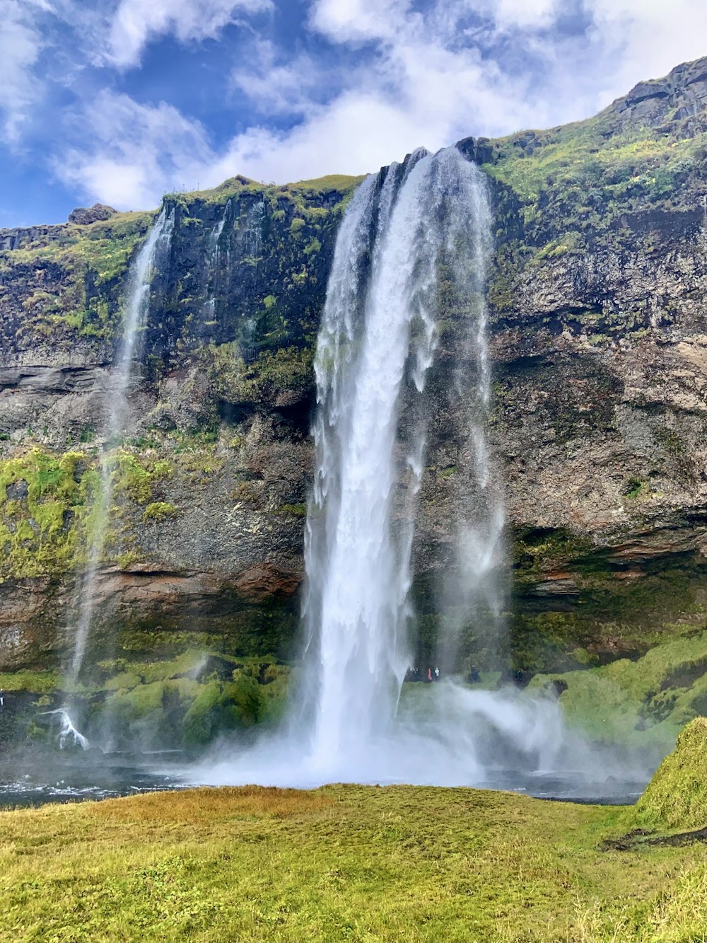 a large waterfall with a man standing in front of it