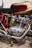 A close-up view of a detailed classic motorcycle engine, featuring polished metal and chrome components. The red and gold color scheme on the bodywork complements the intricate design of the mechanical parts.