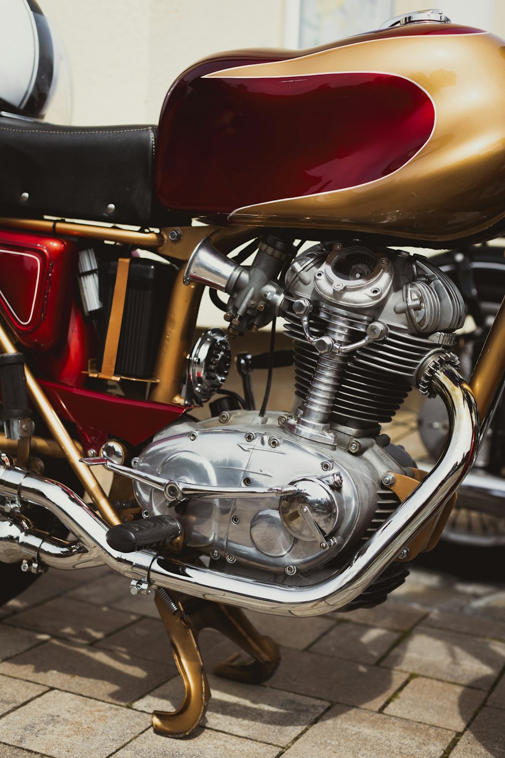 벽돌 보도에 주차된 빨간색과 금색 오토바이
