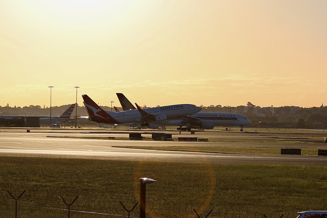 a couple of planes that are on a runway, Qantas B738 taking off 34L with a Singapore airlines taxing to terminal 1