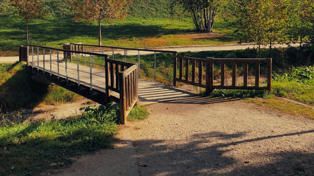 a wooden bridge over a small stream in a park