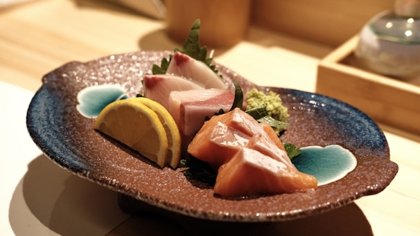 An assortment of sashimi displayed on a white plate with garnishes.