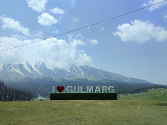 a large sign that says i love gullmarg in front of a mountain