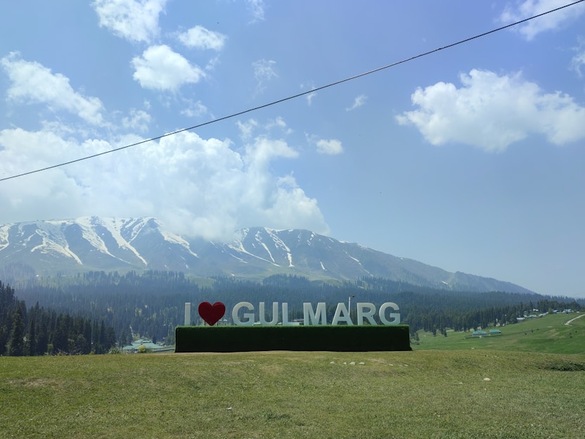 a large sign that says i love gullmarg in front of a mountain