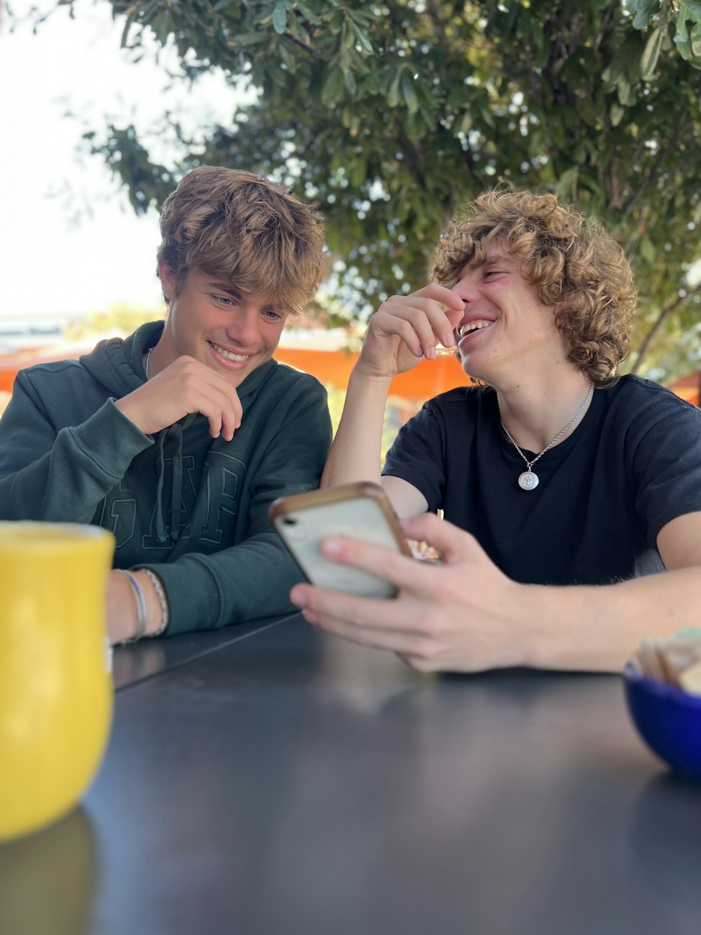 two people sitting at a table with a tablet