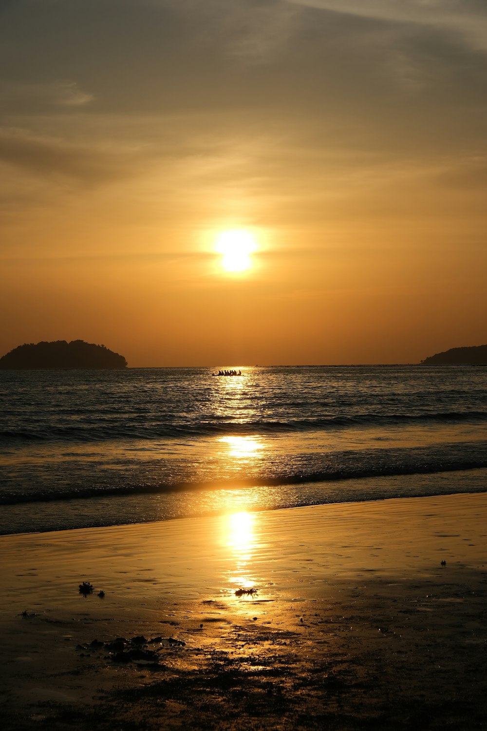 the sun is setting over the water at the beach