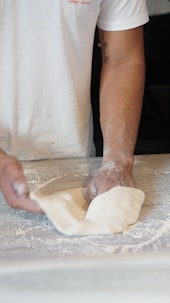 a person kneading dough on top of a table