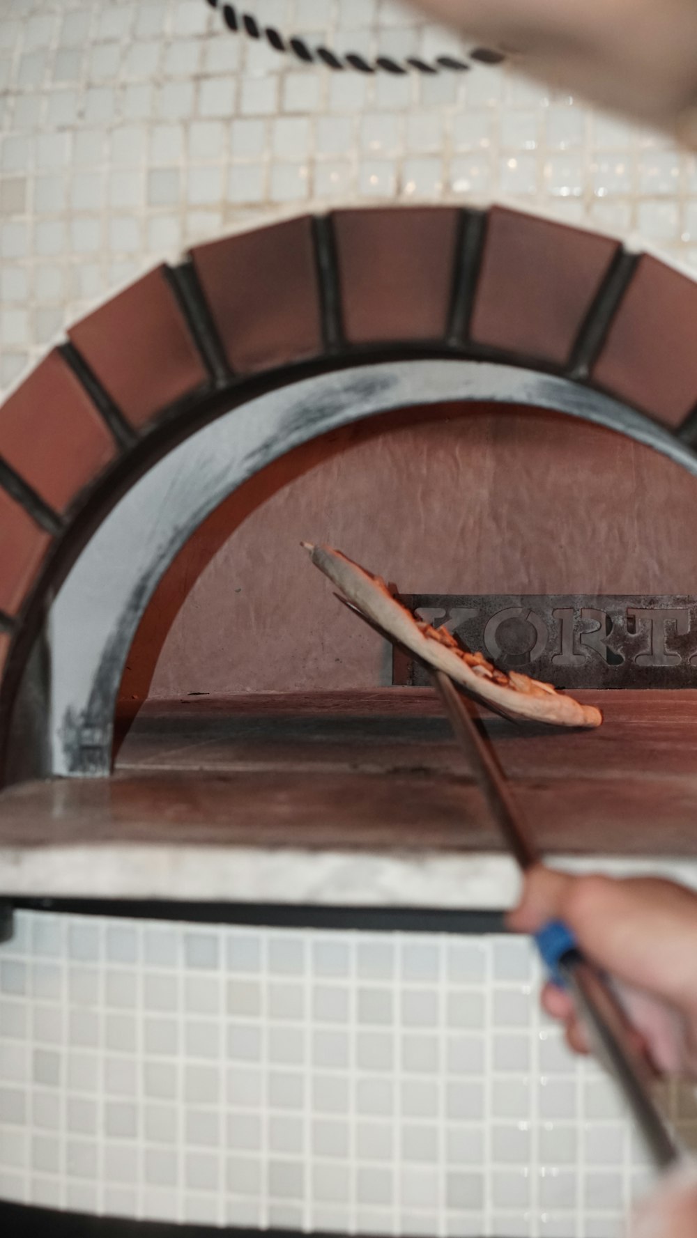 a person pulling a pizza out of an oven