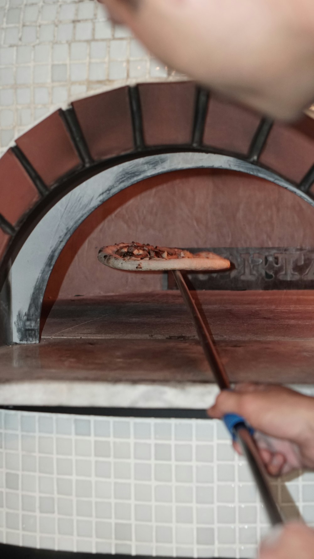 a person putting a pizza in an oven