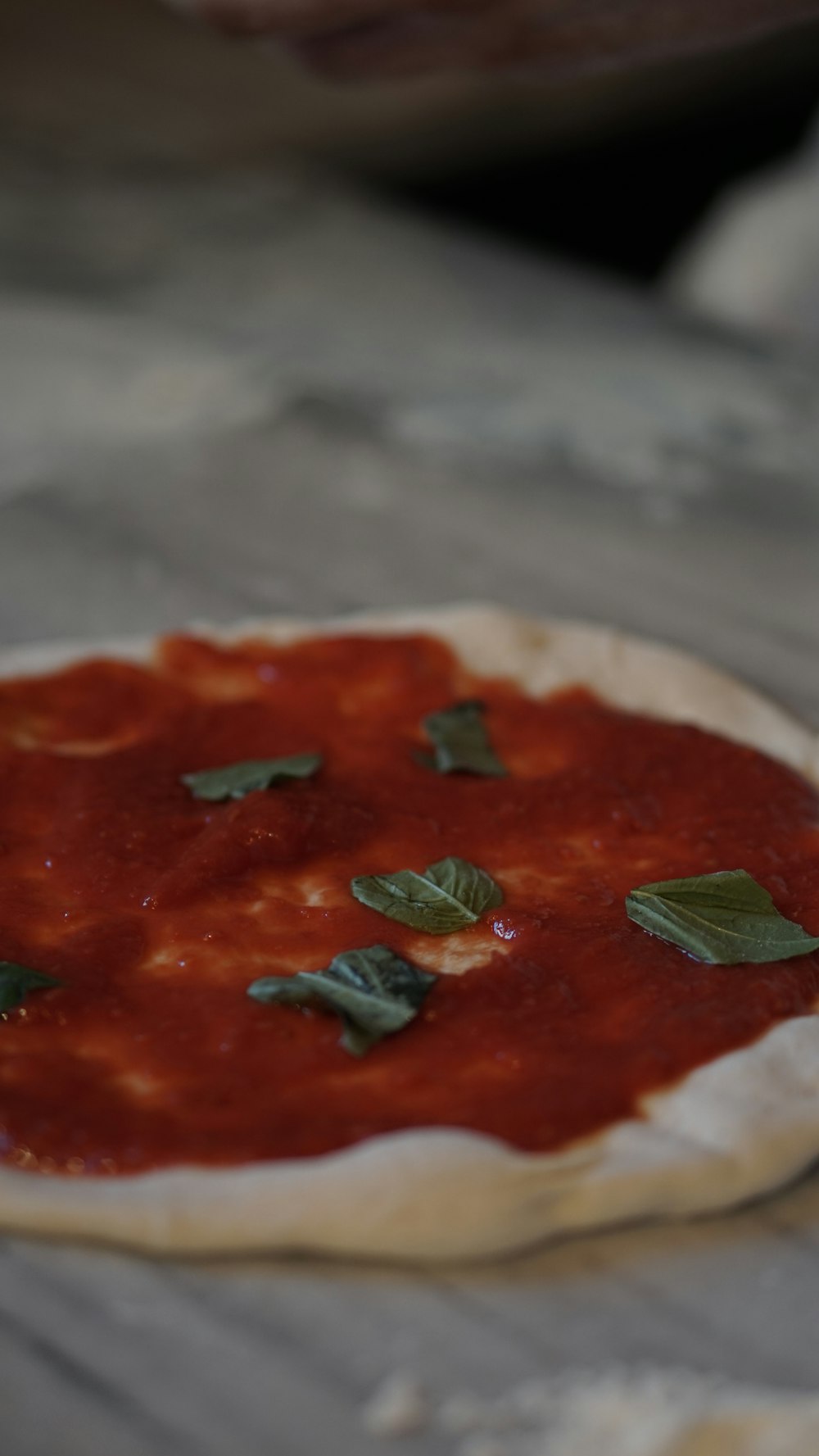 a pizza with sauce and basil on top of it