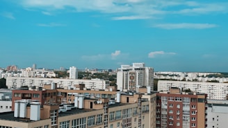 A vibrant cityscape showing a variety of residential buildings including flats and villas under a clear sky.