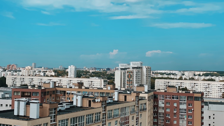 A vibrant cityscape showing a variety of residential buildings including flats and villas under a clear sky.