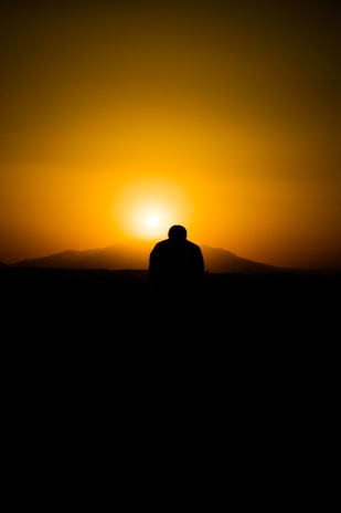 A cinematic shot of a golden hour landscape with a lone figure silhouetted against the sky.