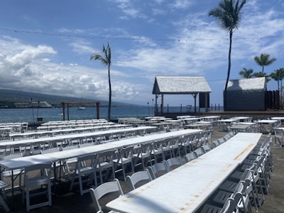 Rows of white event tents set up on a tropical beach under clear blue skies.