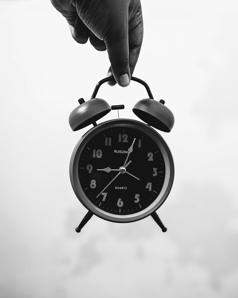 a black and white photo of a person holding an alarm clock
