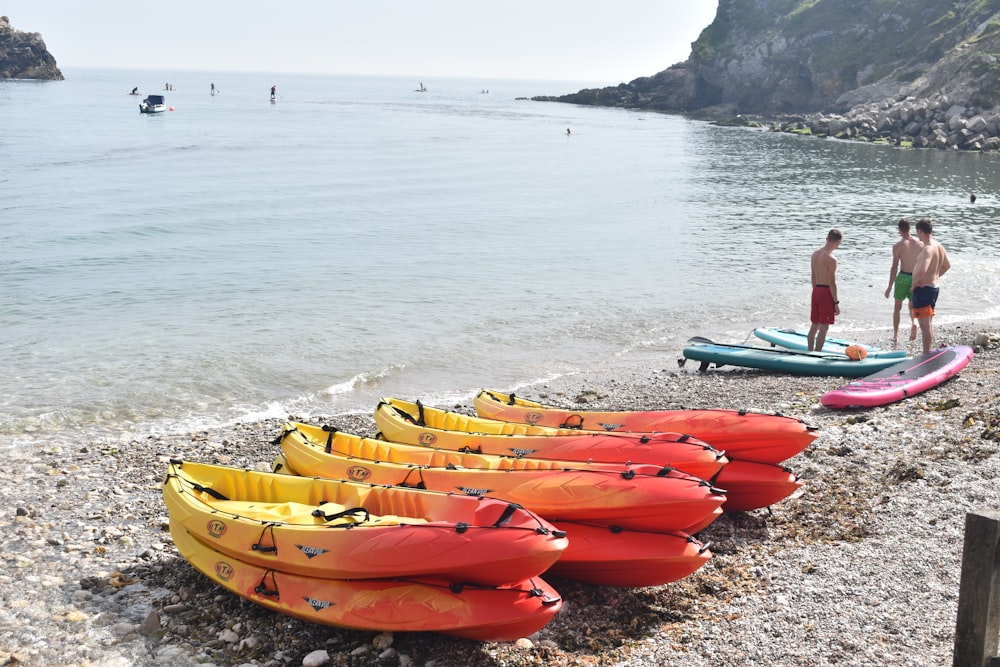 a group of people standing on a beach next to kayaks