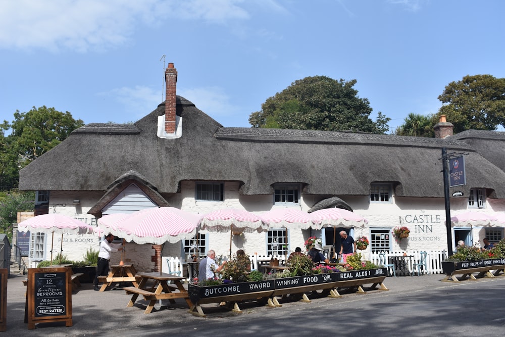 a white building with a thatched roof and pink umbrellas