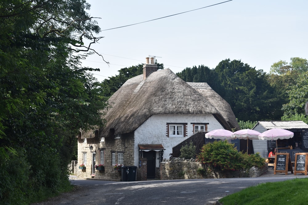 a white house with a thatched roof and two pink umbrellas