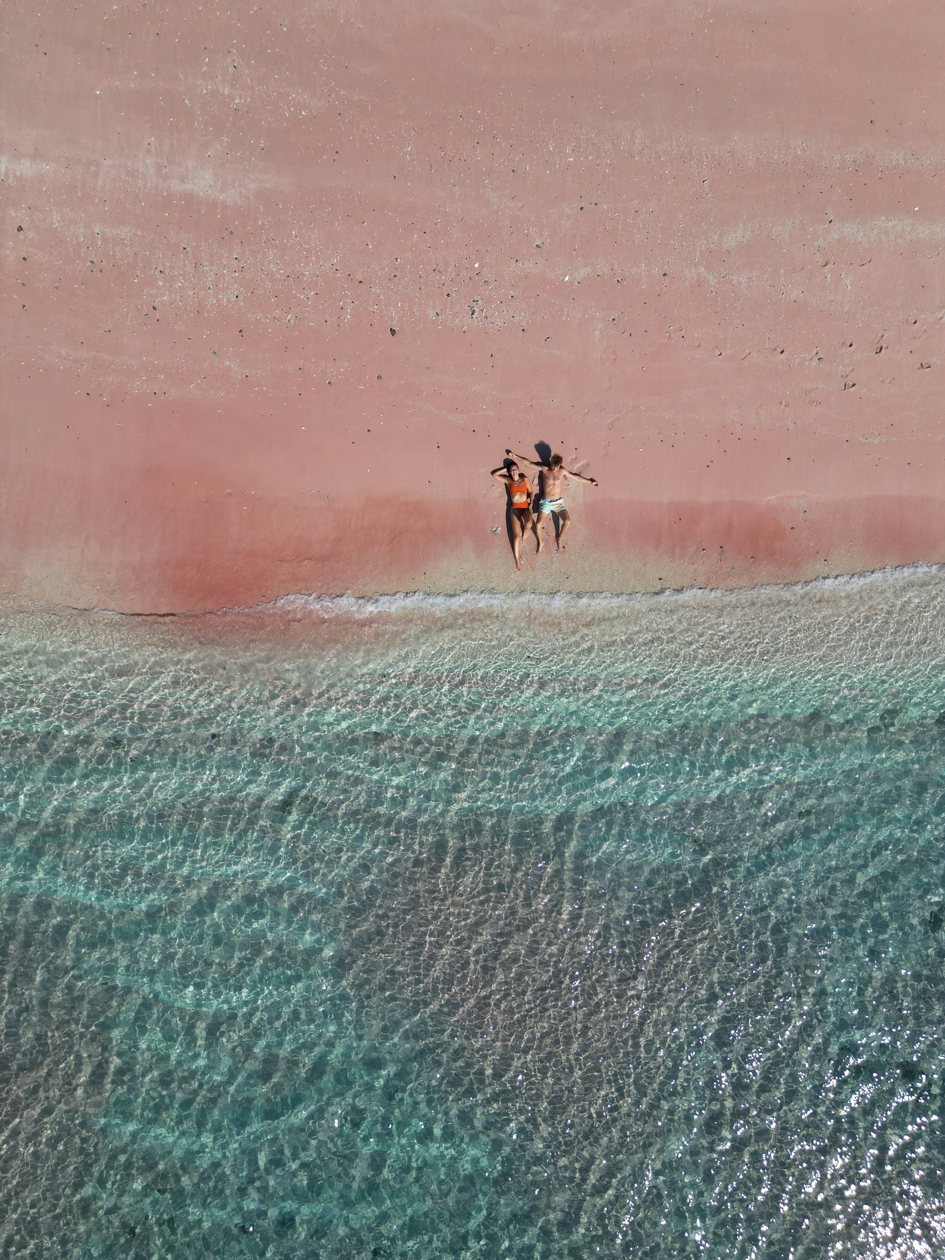 a couple of people riding horses on top of a beach