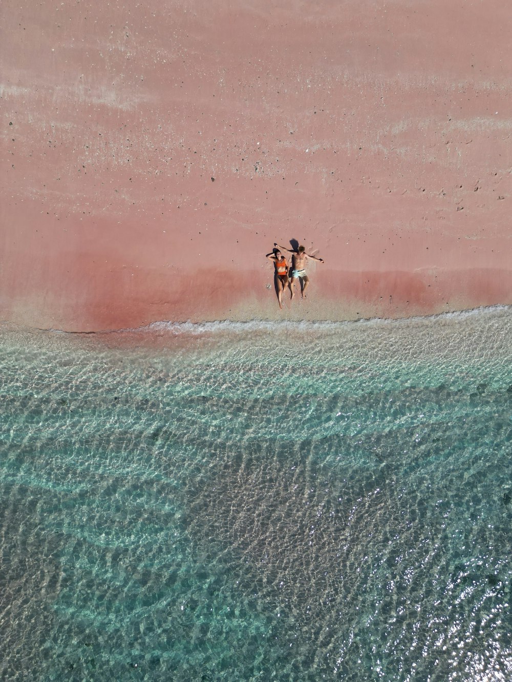 a couple of people riding horses on top of a beach