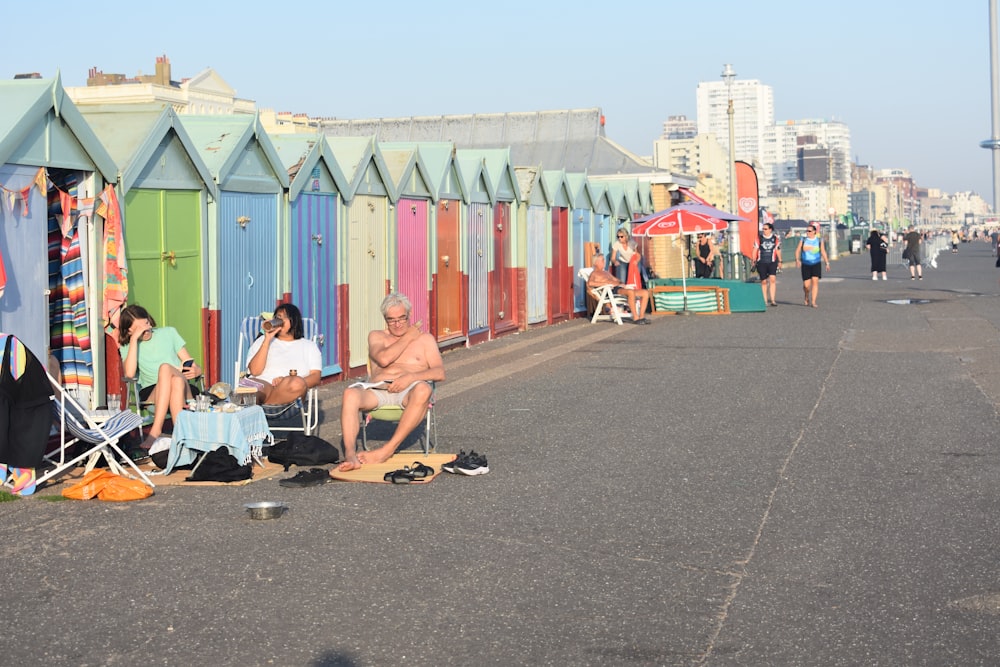 a man sitting on a chair next to a row of beach huts