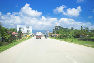 Delivery truck carrying a generator, driving through a scenic rural road.