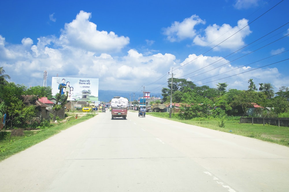 a truck driving down a road next to a lush green field