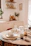 A warm kitchen scene with elegant ceramic crockery arranged on a wooden dining table bathed in soft natural light.