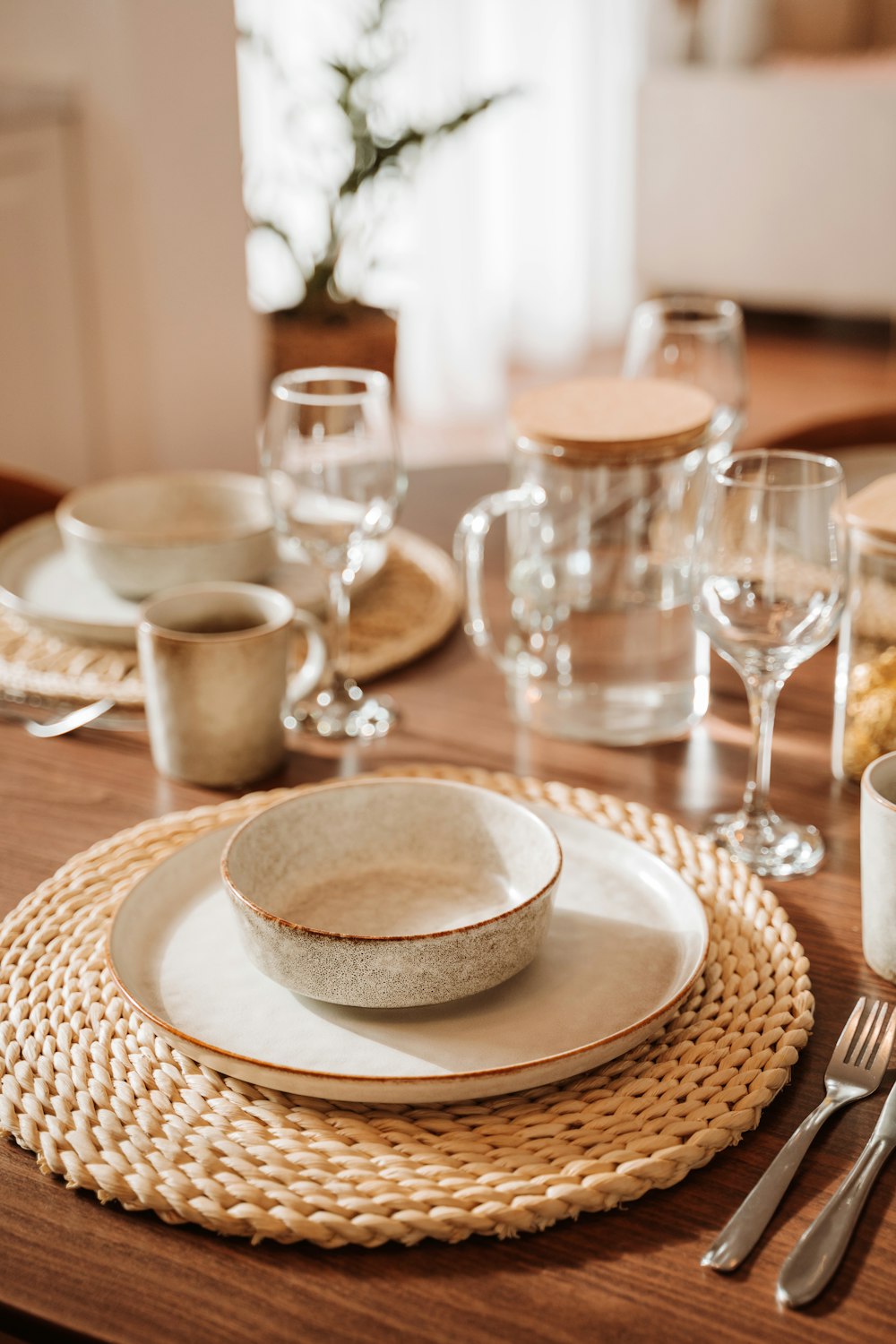 a table set with a bowl, plate and glasses