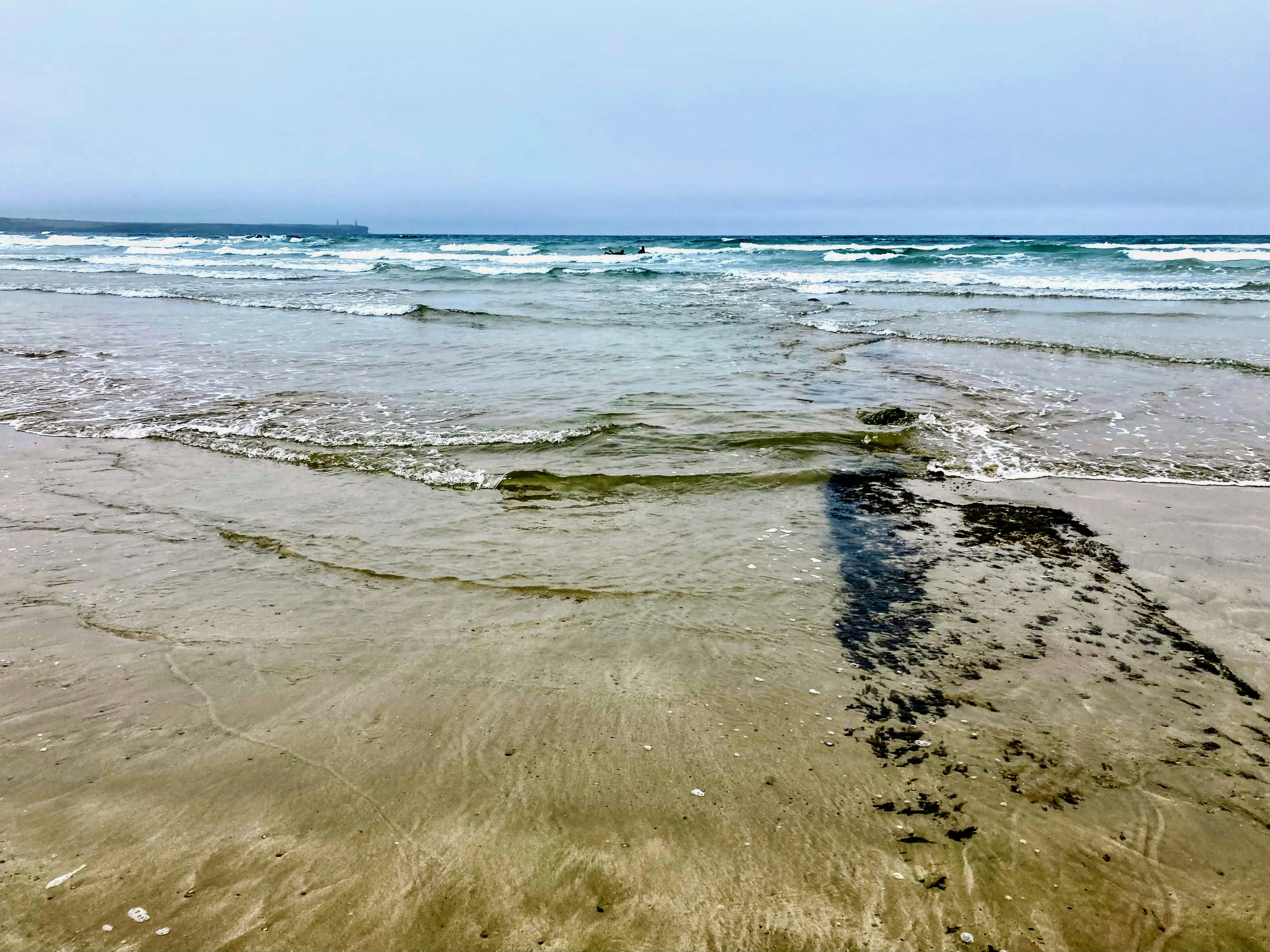 a sandy beach with waves coming in and out of the water