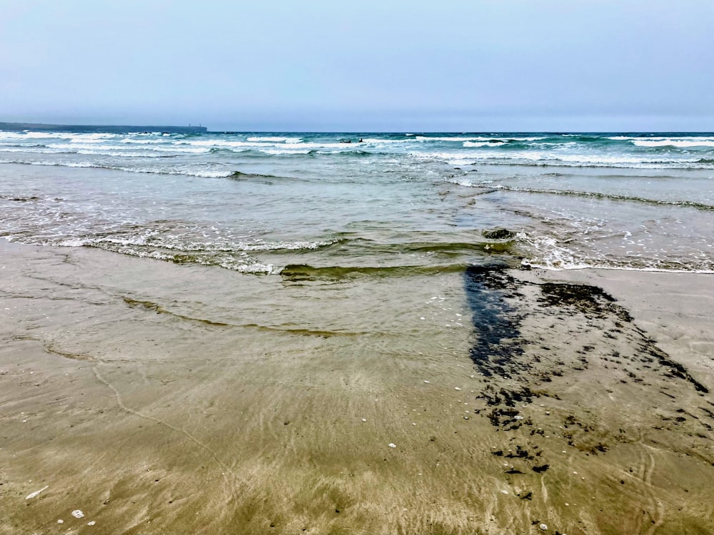 ein Sandstrand mit Wellen, die ins und aus dem Wasser kommen