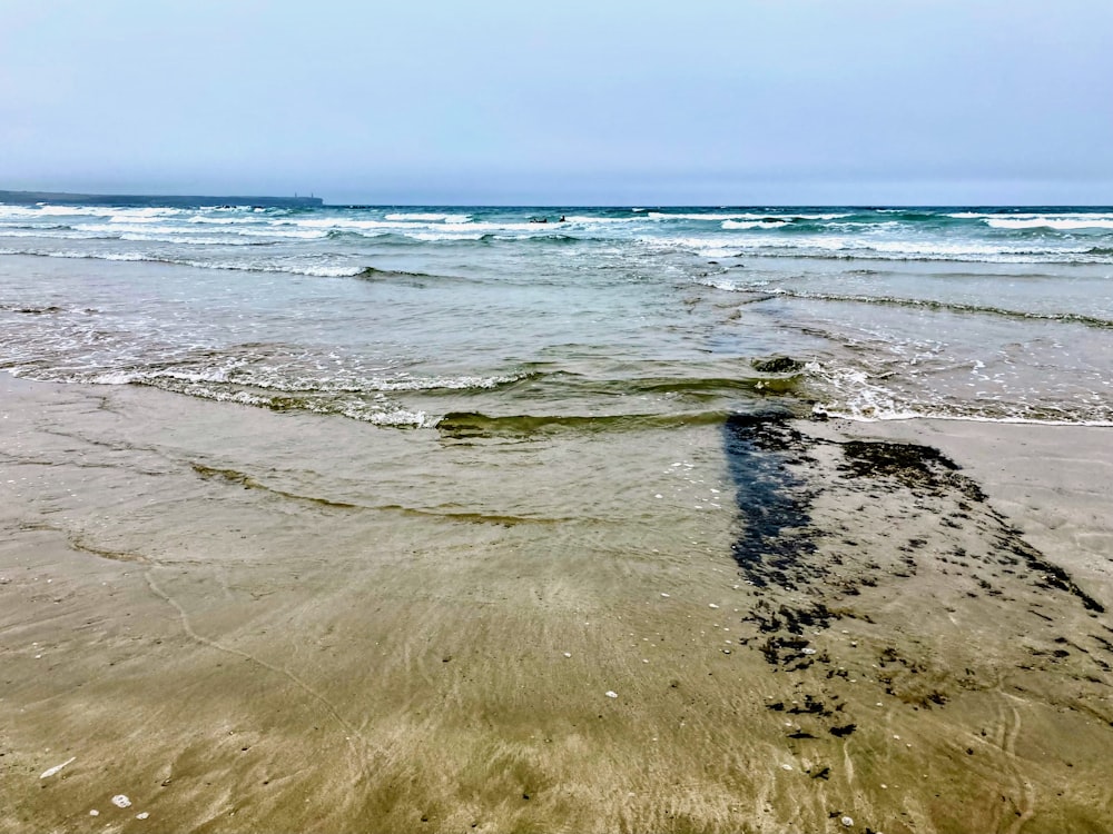 a sandy beach with waves coming in and out of the water