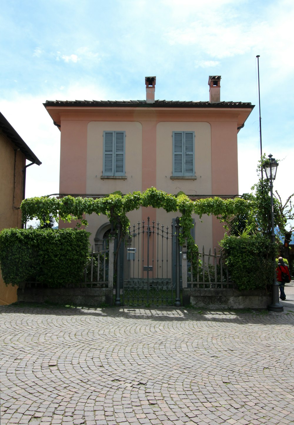a pink house with a gate and some bushes