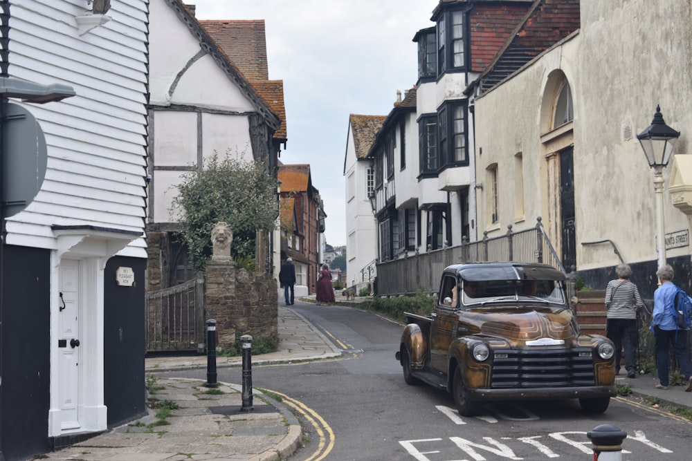 an old car is driving down a narrow street