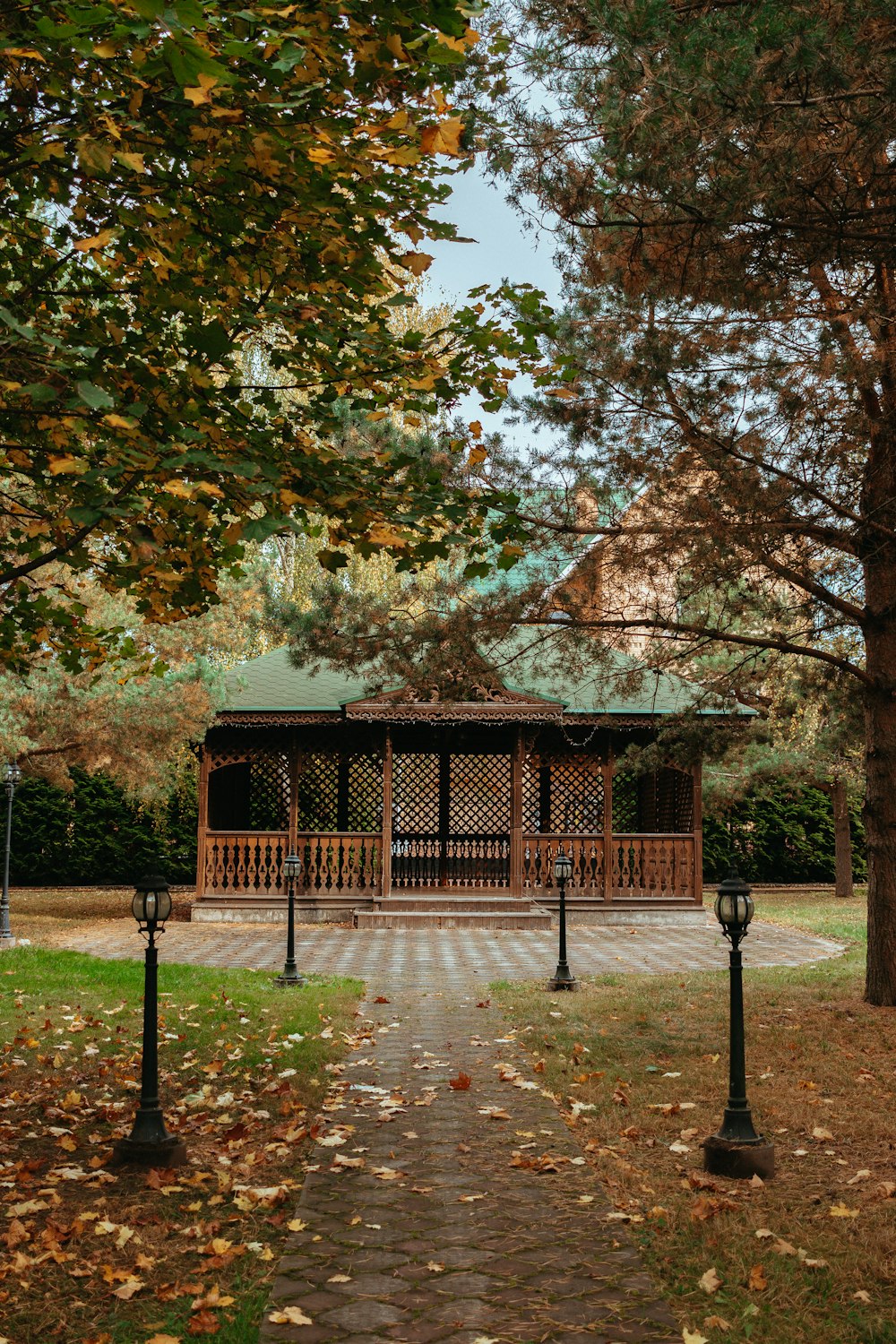 a wooden gazebo surrounded by trees in a park