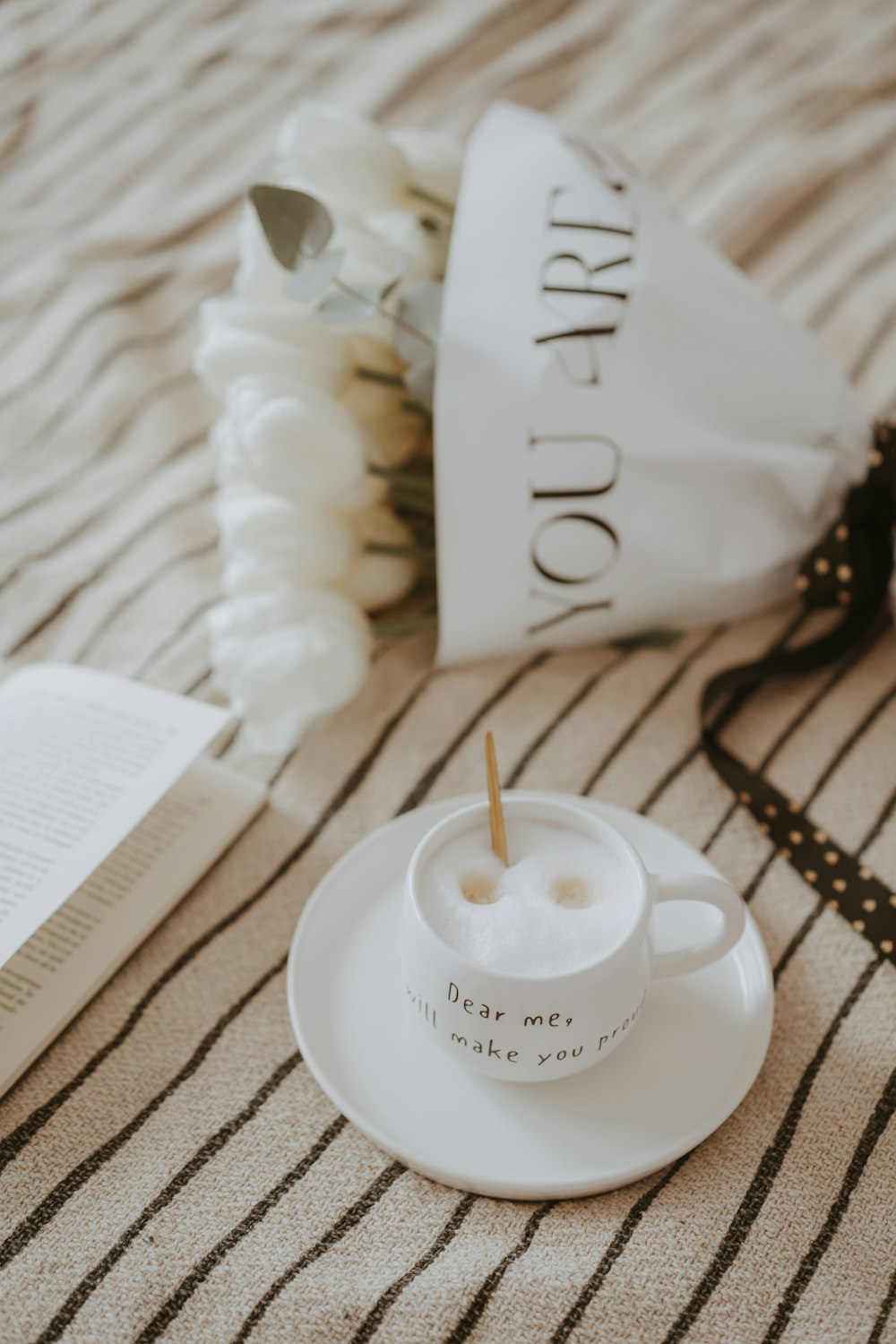 a cup of coffee on a saucer next to a book