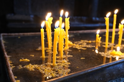 Handcrafted beeswax candles glowing warmly on a rustic wooden table with yellow accents.