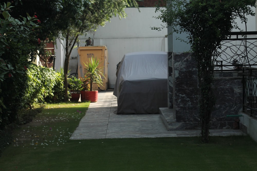 a car covered with a sheet parked in a back yard