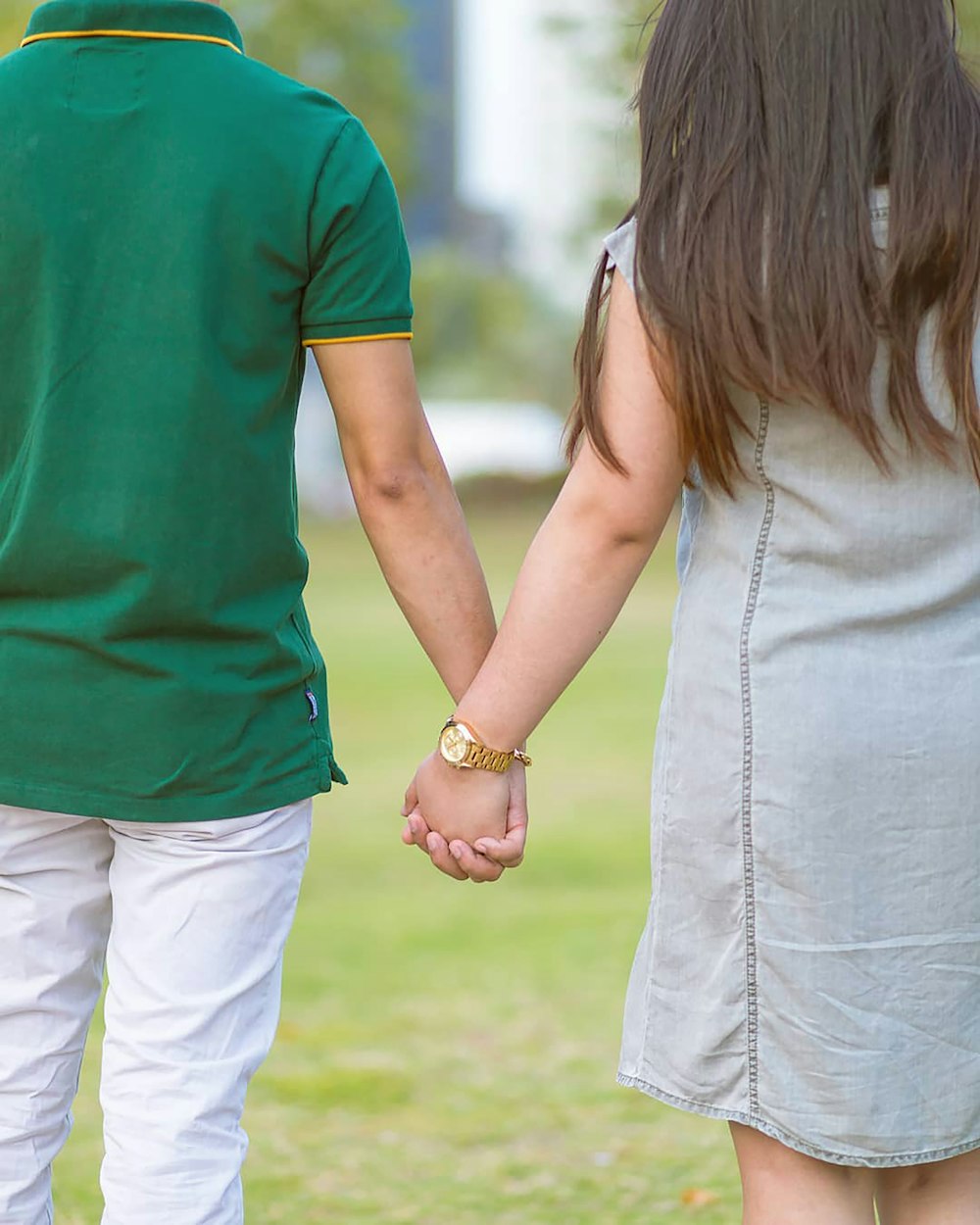 a man and a woman holding hands in a park